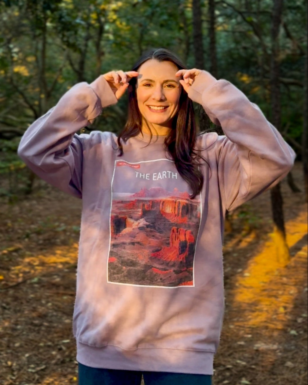 Woman wearing a sweatshirt with a graphic design in a forest setting