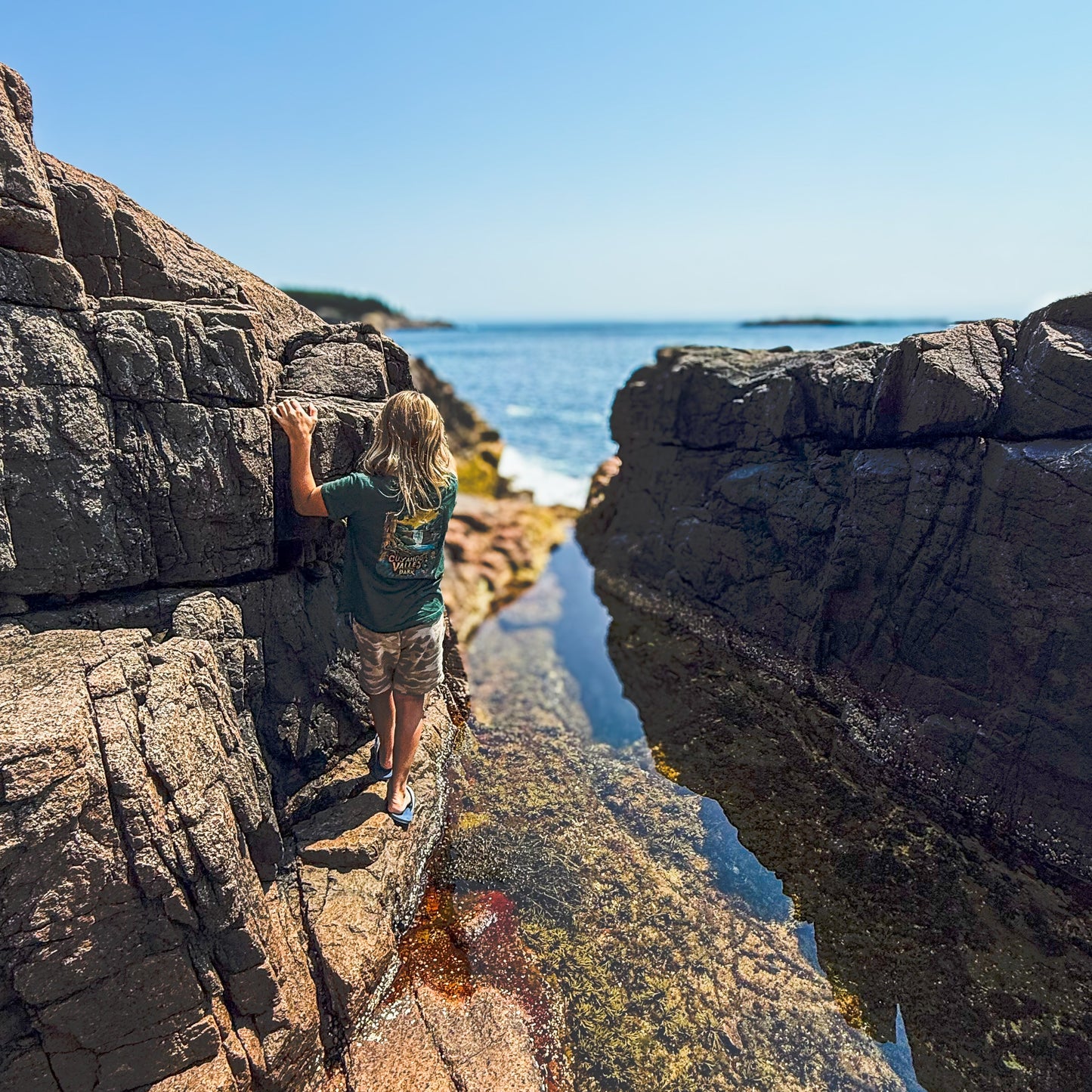 Child exploring rocky shore in youth Cuyahoga Valley National Park Tee, celebrating nature and adventure.