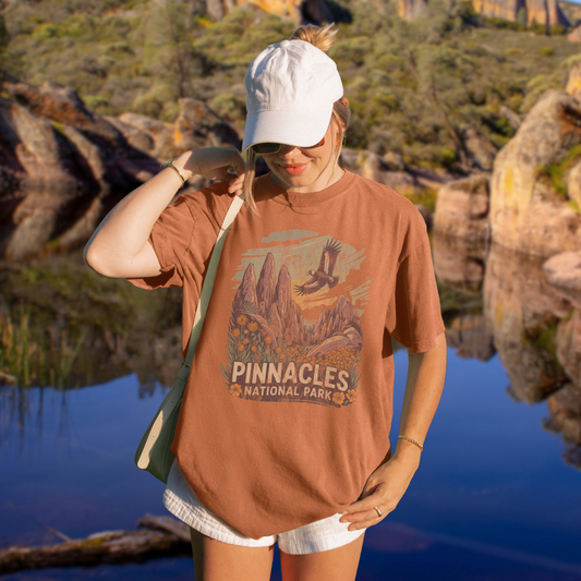 Person wearing a Pinnacles National Park Shirt against a scenic outdoor background featuring rugged peaks and nature.