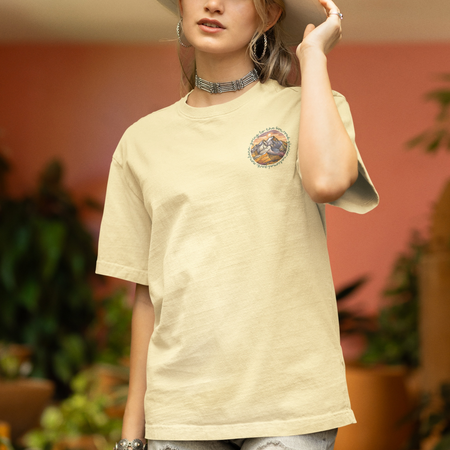 Woman wearing a beige Going to the Sun Road T-shirt featuring Glacier National Park design, with nature-inspired graphics.