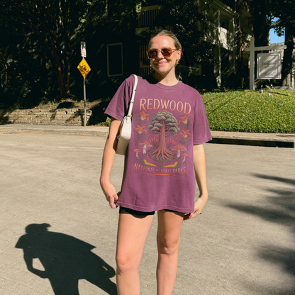 Woman wearing a Redwood National Parks tee, showcasing nature-inspired design in a sunny outdoor setting.