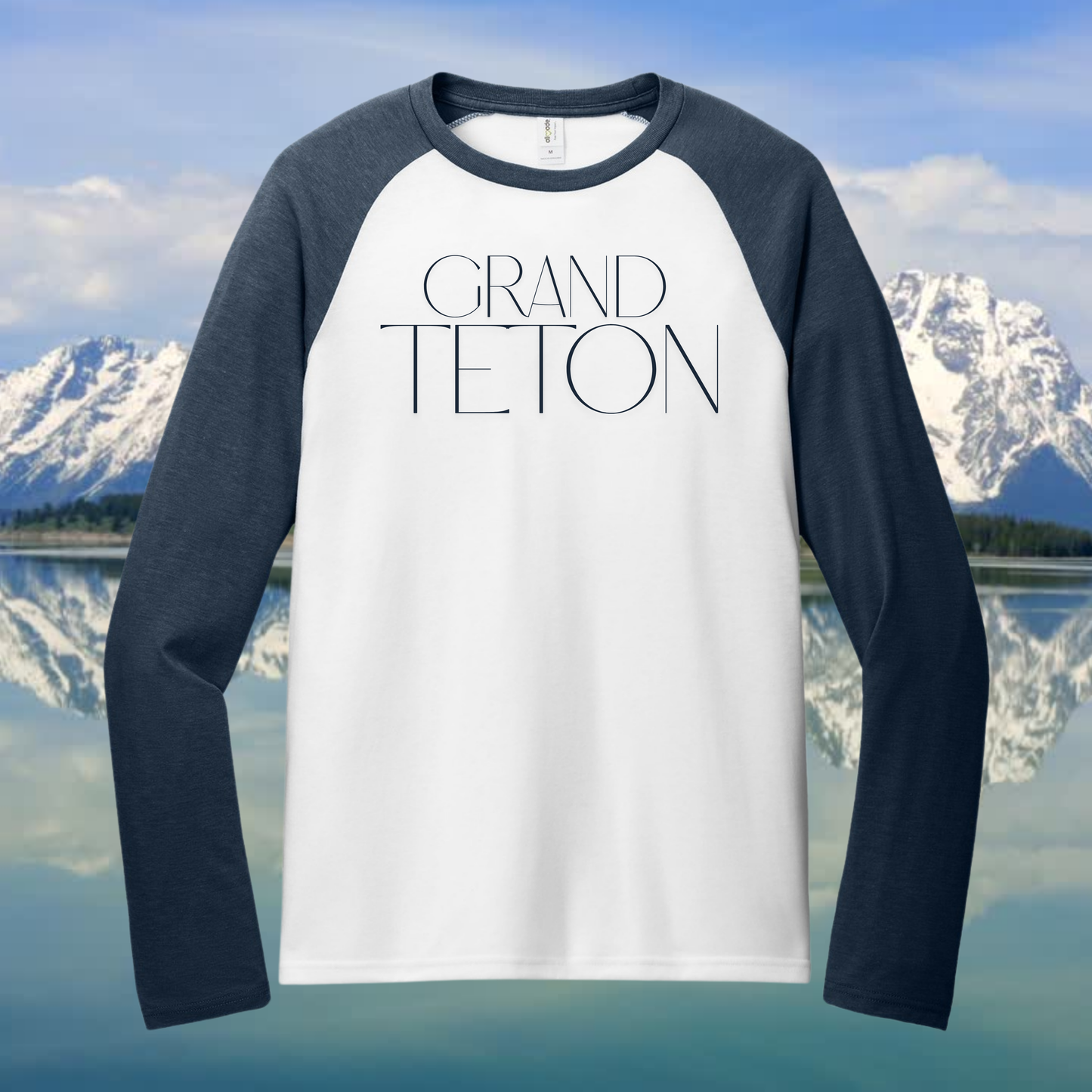 Grand Teton raglan tee featuring modern design with blue sleeves and minimalist typography against mountain backdrop.