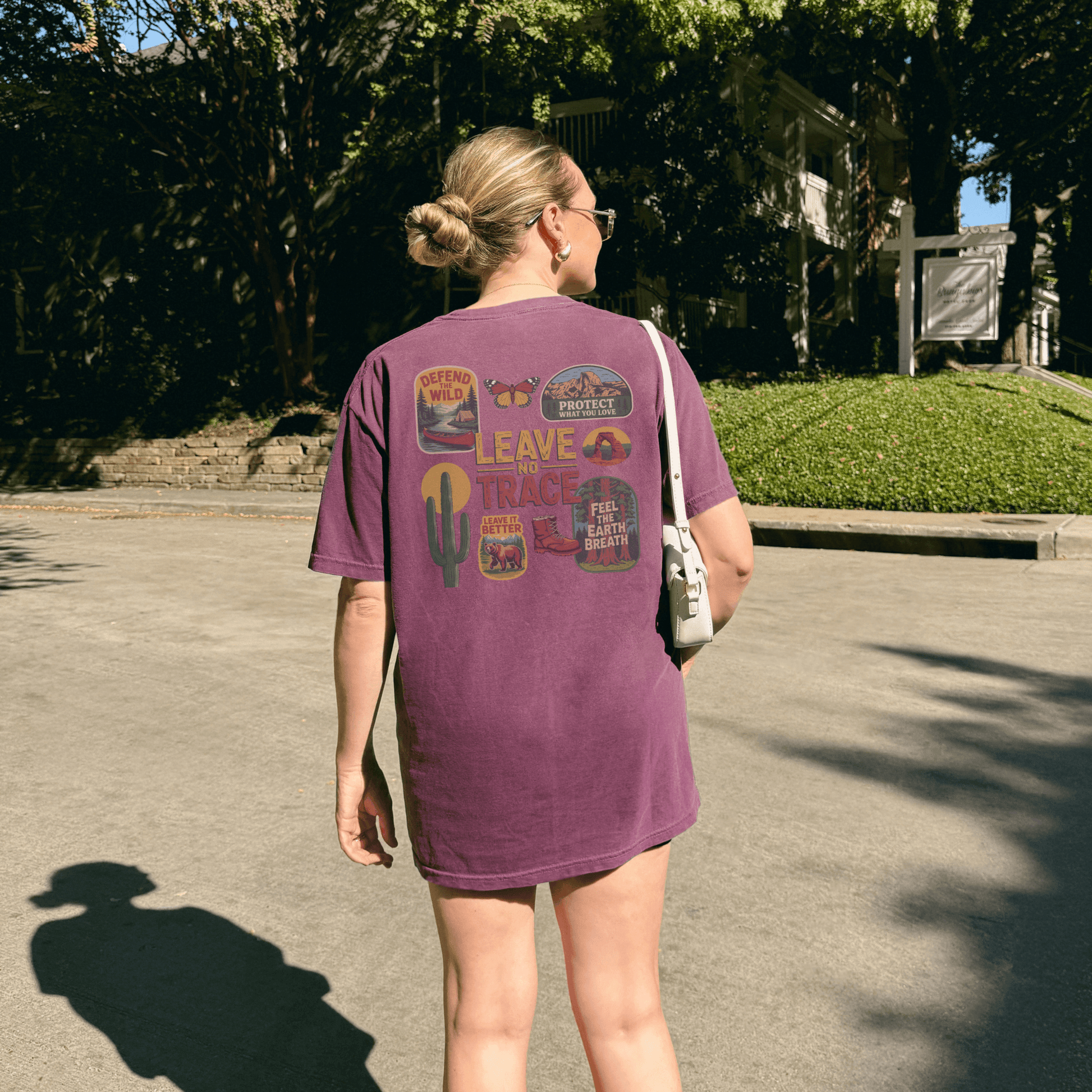 Back view of a woman wearing a Leave No Trace tee with vintage-inspired graphics and patches.