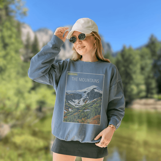 Woman wearing The Mountains Crewneck - Nature Library Series in a scenic outdoor setting.