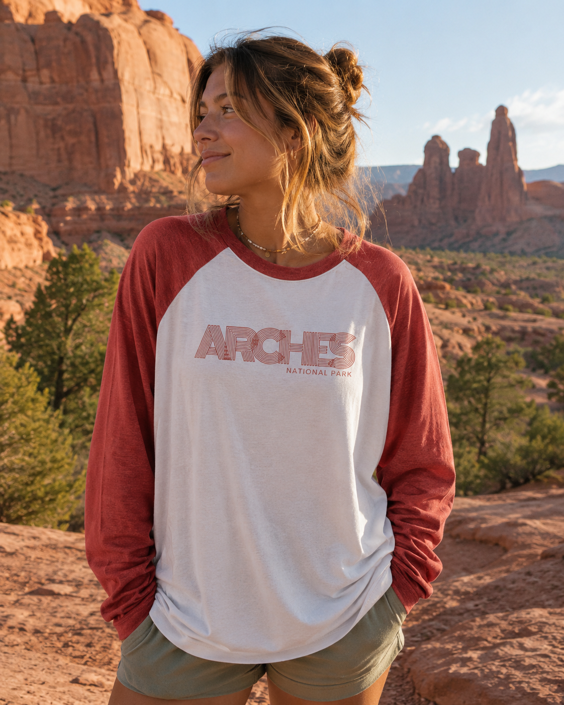 Woman wearing the Arches Heritage Raglan Tee in a scenic desert landscape with red rock formations.