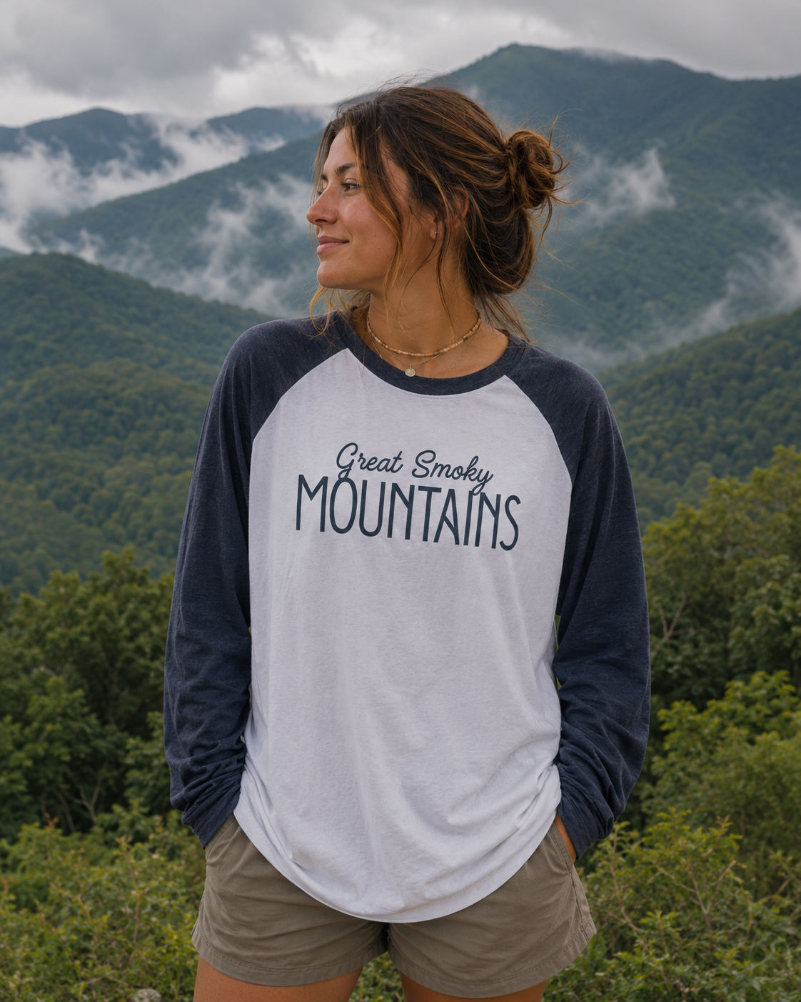 Woman wearing Great Smoky Mountains tee in front of scenic mountain landscape.