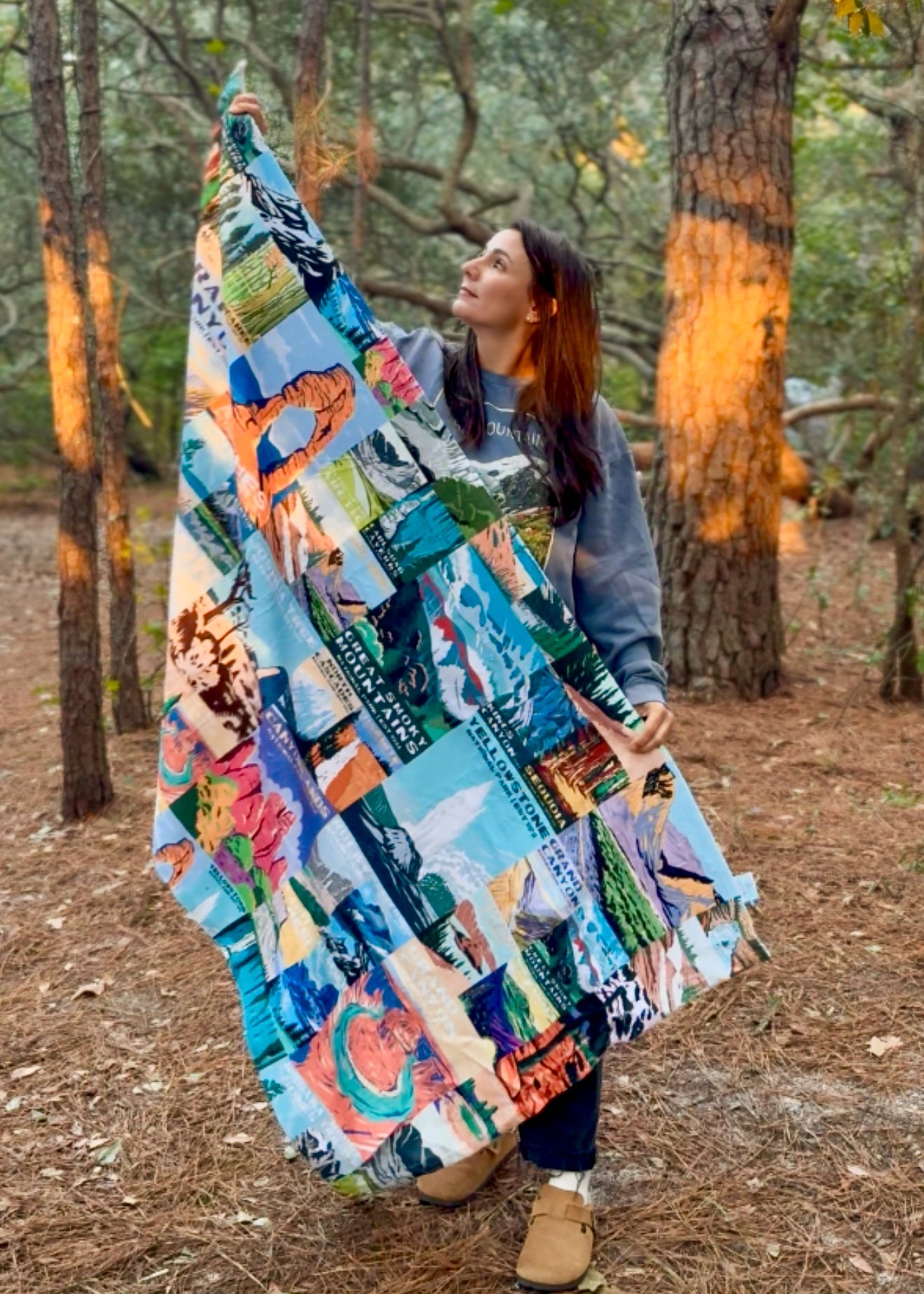 Woman holding a colorful national parks towel outdoors in a forest setting