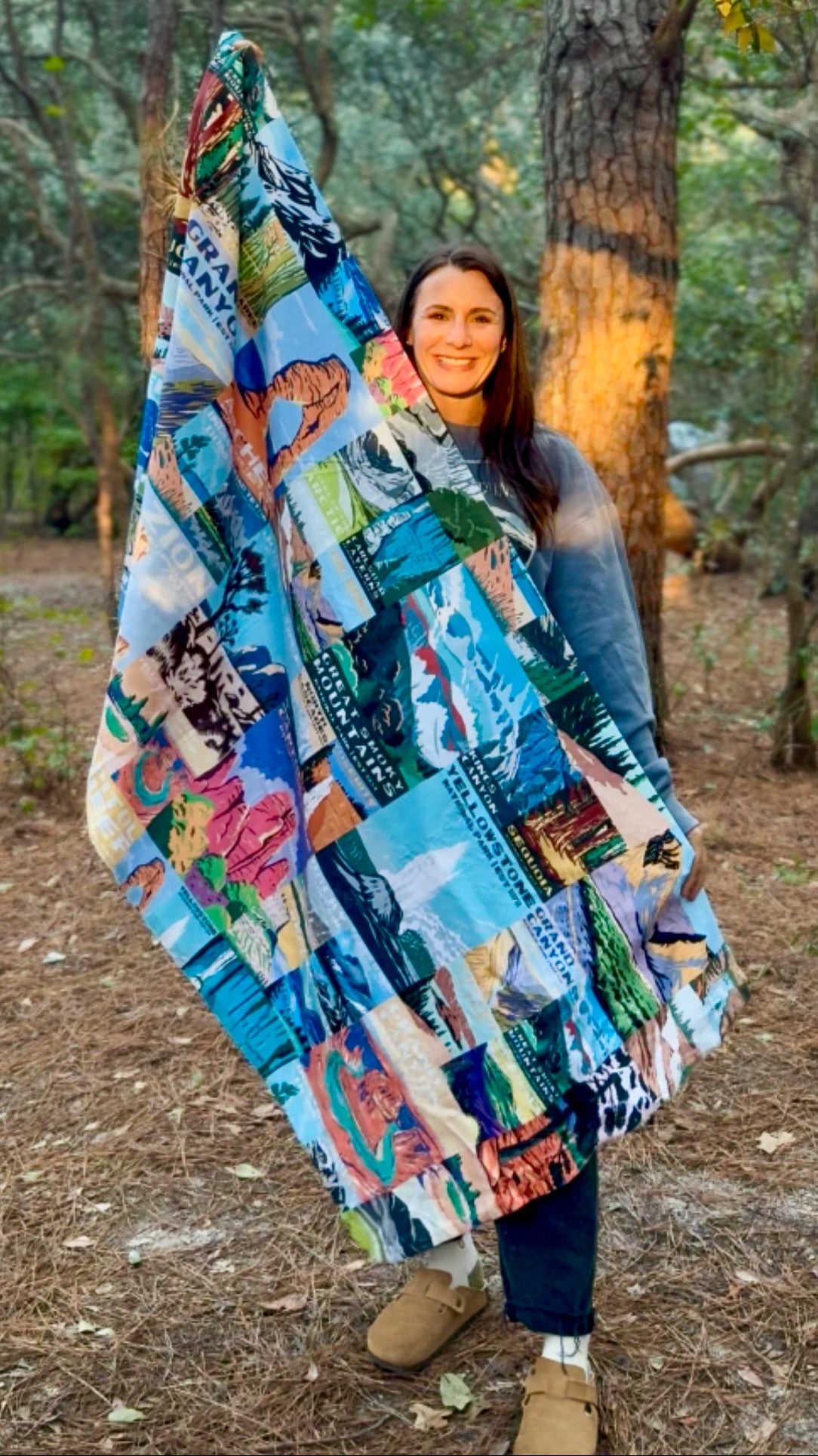 Woman holding a colorful national parks towel outdoors in a forest setting