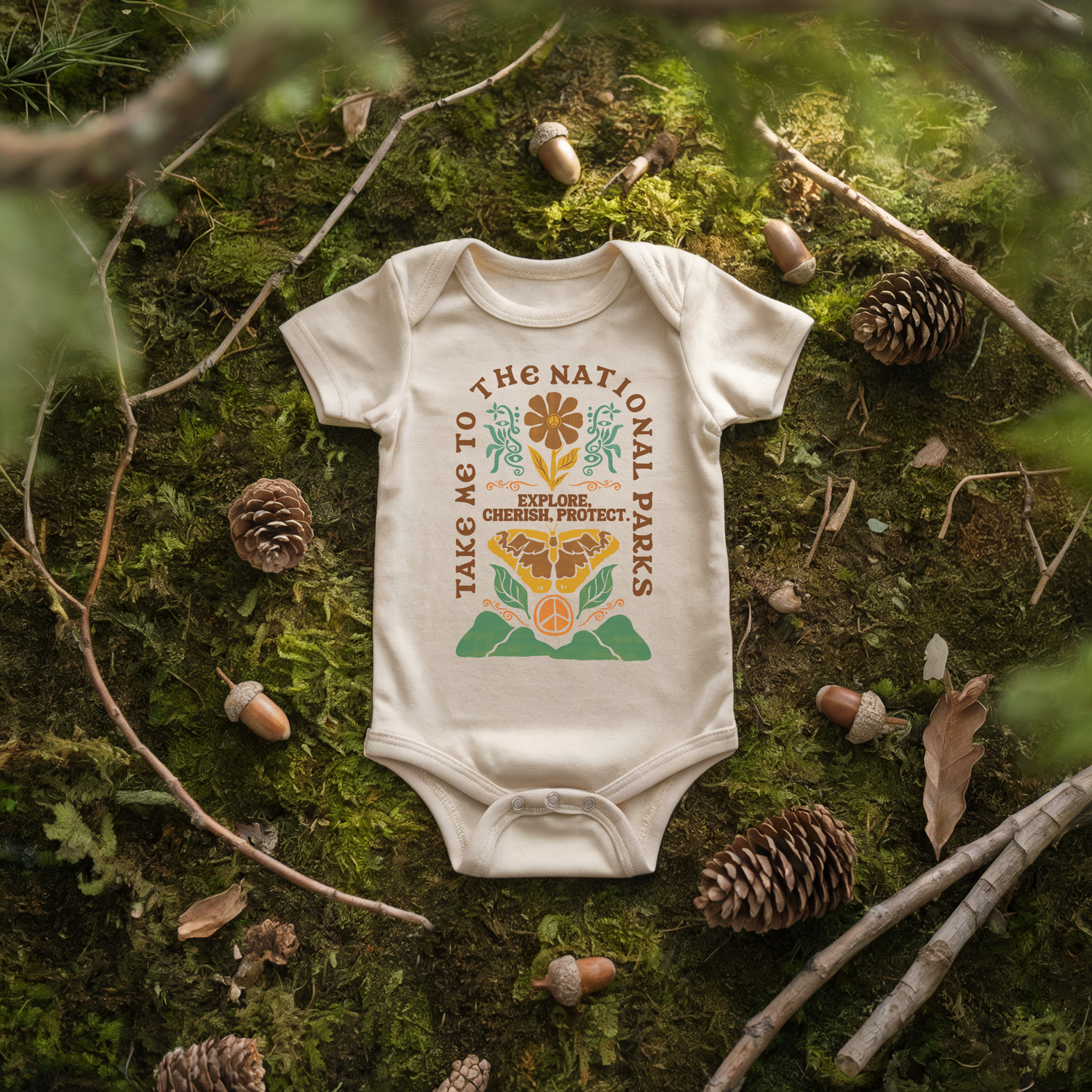Take Me to the National Parks baby onesie with floral and mountain design on moss background.